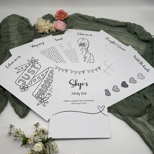 Set of black and white activity sheets from children's activity pack on a green fabric background with flowers.