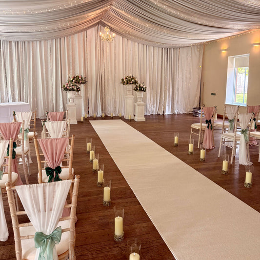 Decorated event space with chairs, candles, and a white aisle runner.