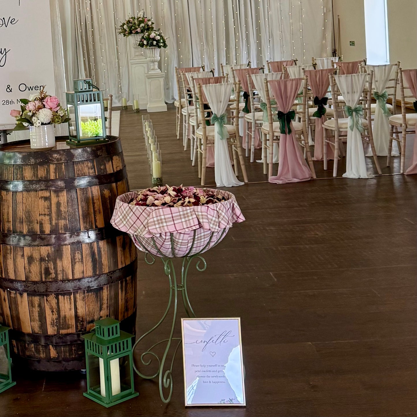 Decorated wedding venue with chairs, floral arrangements, whiskey barrel and a confetti basket.