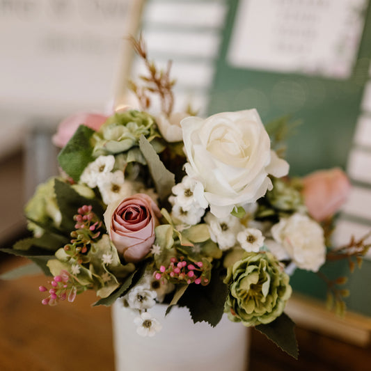 Floral arrangement with white, pink, and green flowers in a white vase.