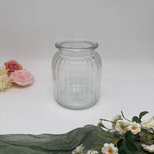 Medium textured glass vase surrounded by flowers on a white background.