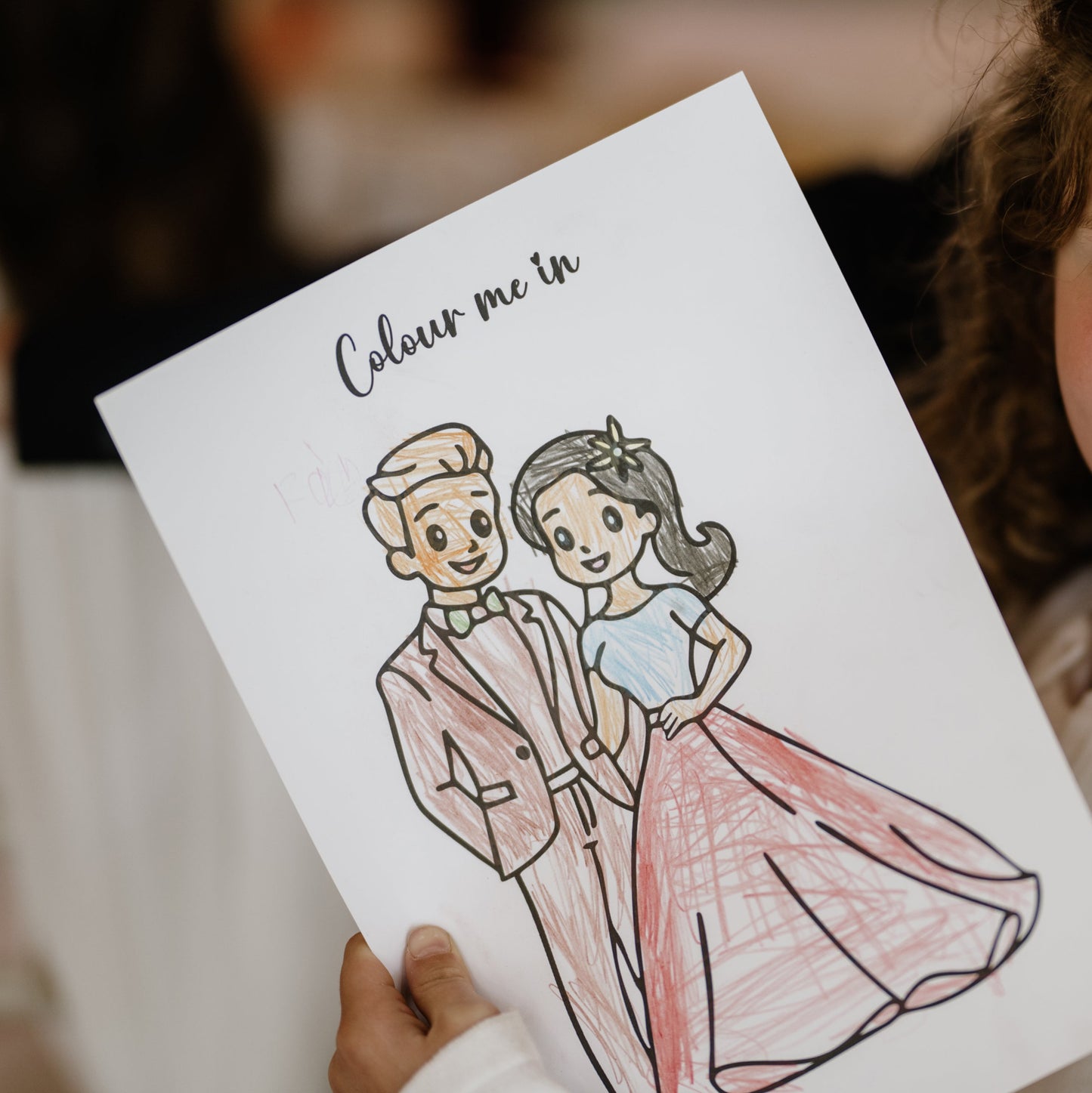 Child holding a coloring page with a couple illustration from activity pack
