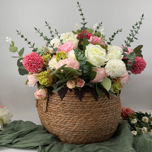 Floral arrangement in a woven basket sitting on a green fabric cheesecloth