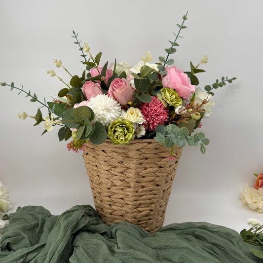 Wicker basket filled with a colorful arrangement of flowers on a green fabric background