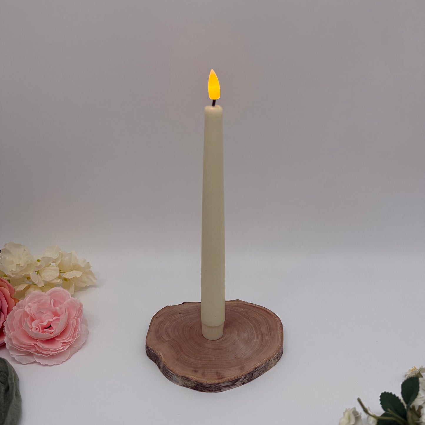 Candle on a wooden coaster with flowers on a white background