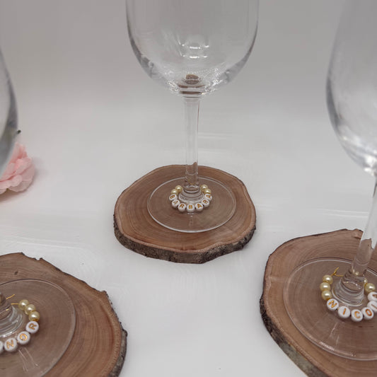 Wine glasses on wooden coasters with decorative beads on a white surface