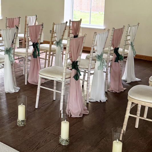 Decorated chairs with pink and white ribbons on a wooden floor.