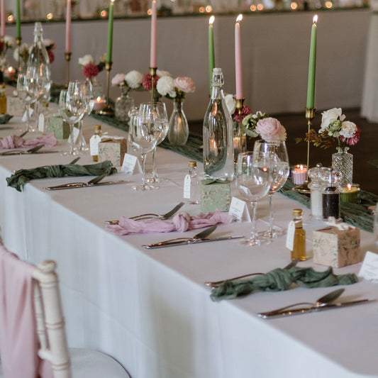 Decorated table with candles, glasses, and flowers in a formal setting with napkins.