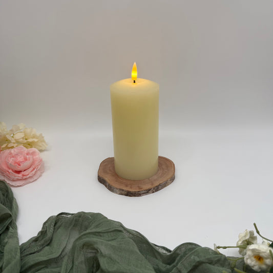 Candle on a wooden coaster with flowers and fabric on a white background