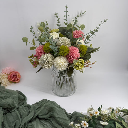 Bouquet of artificial flowers in a clear vase on a white background