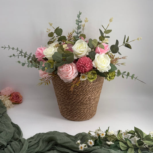 Wicker basket with pink, white, and green flowers on a white background