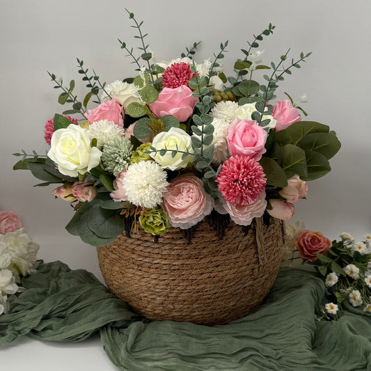 Floral arrangement in a woven basket sitting on a green fabric cheesecloth