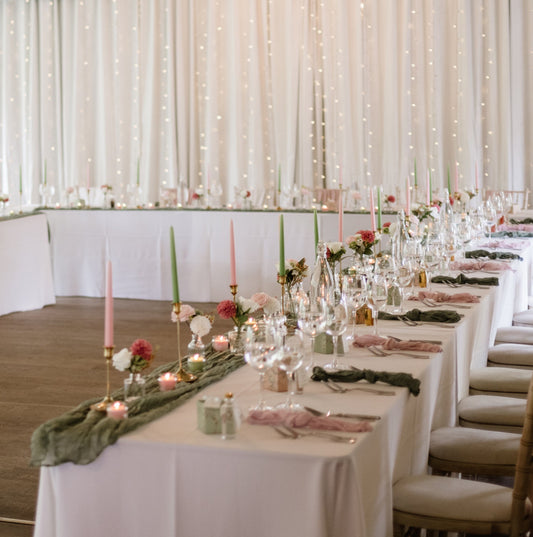 Wedding reception setup with tables, chairs, and decorations in a large room.